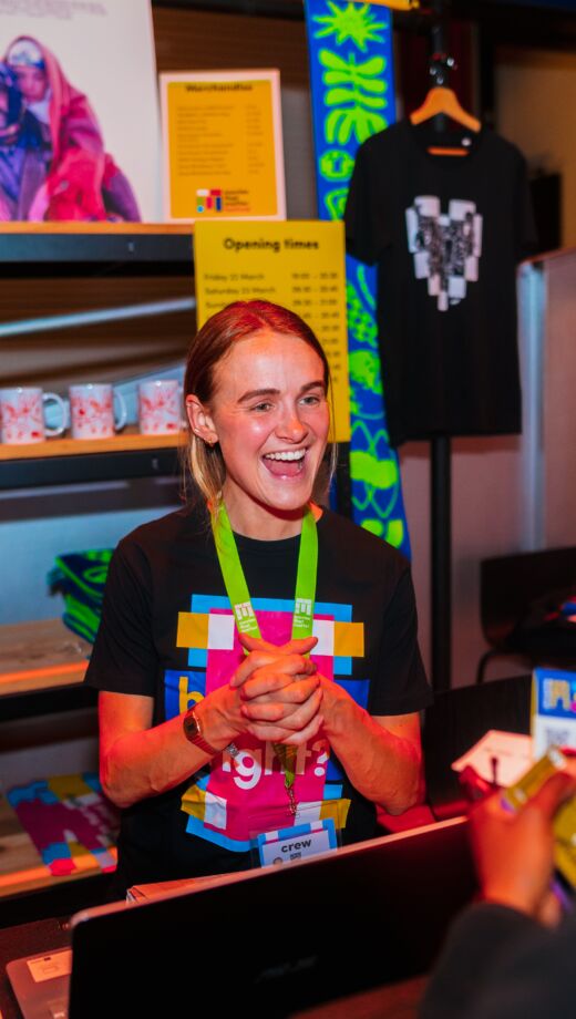 festivalmederwerker bij merchandise kraam in gesprek met festivalbezoeker