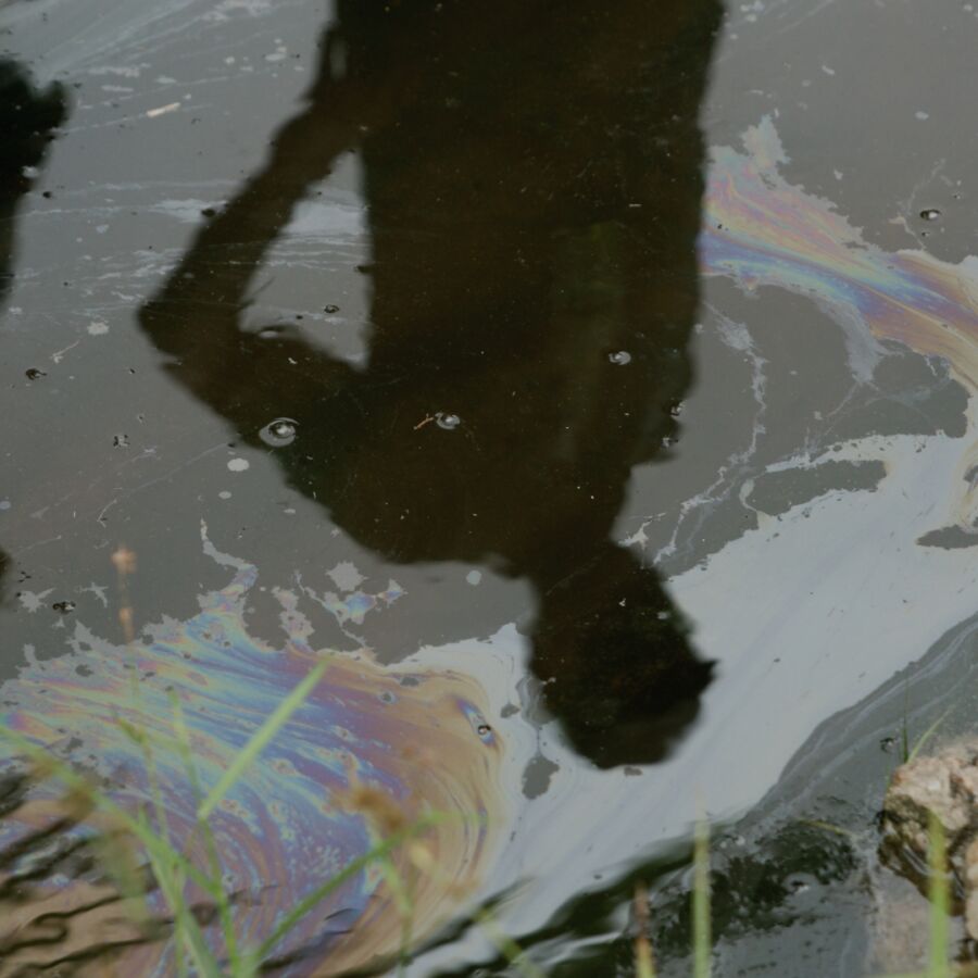 Reflections of two people in an oil slick on the ground