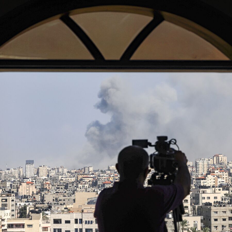 An AFPTV cameraman films while smoke plumes billow during Israeli air strikes in Gaza City on October 12, 2023 as raging battles between Israel and the Hamas movement continue for the sixth consecutive day. Thousands of people, both Israeli and Palestinians have died since October 7, 2023, after Palestinian Hamas militants based in the Gaza Strip, entered southern Israel in a surprise attack leading Israel to declare war on Hamas in Gaza on October 8. (Photo by MOHAMMED ABED / AFP)