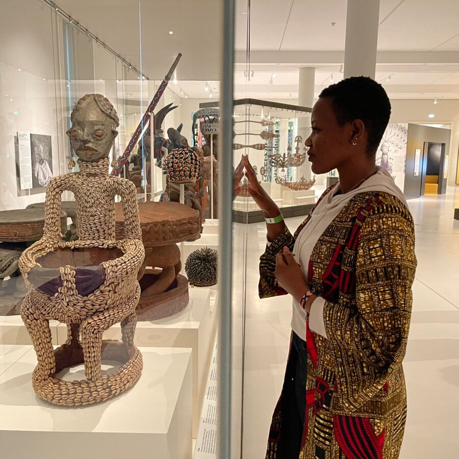 Person gazes into a glass sealed box containing a Cameroonian artwork inside a museum 