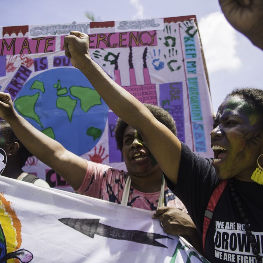 Group of young people from the South Pacific protest with paint on their face and colourful banners with texts as: "Climate Change" and "We are drowning. We are fighting."