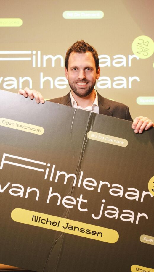 Docent Nichel Janssen houdt een cheque vast met de titel Filmleraar van het Jaar